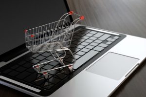 Computer generated image of shopping cart on laptop. E-commerce concept.